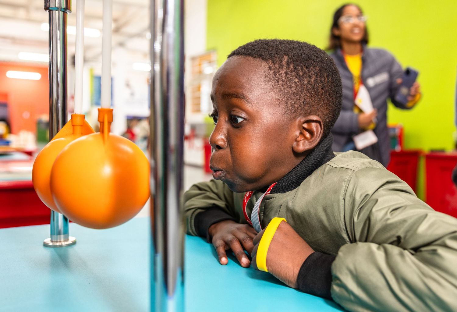 Children conduct physics experiments with balls and tubes in a bright classroom setting.