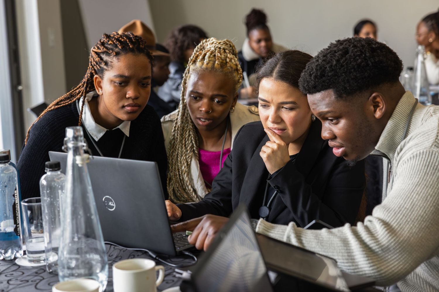 Students gathered around a table engaged in focused discussion during a learning session.