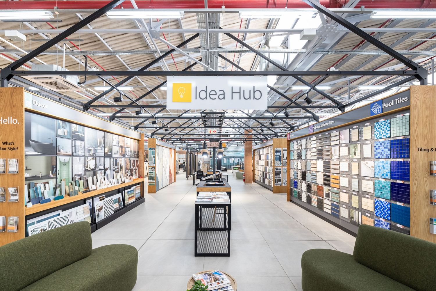 Industrial-style workspace with exposed ceiling, idea hub signage, and collaborative areas under skylight windows.