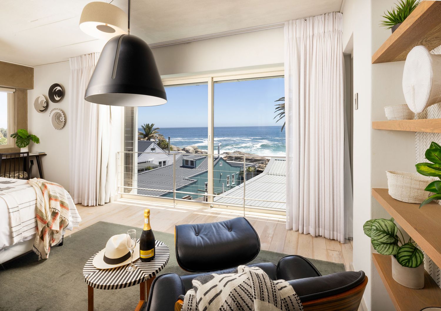 Modern coastal living room with leather chair and ocean view through large windows, featuring natural decor elements.