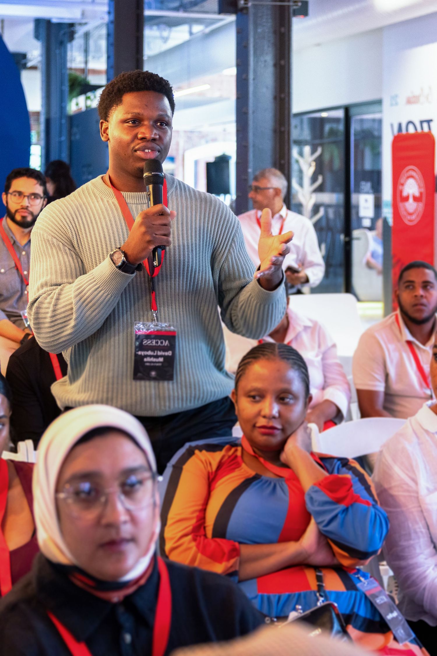 Audience members participating in an interactive presentation with red branding elements.