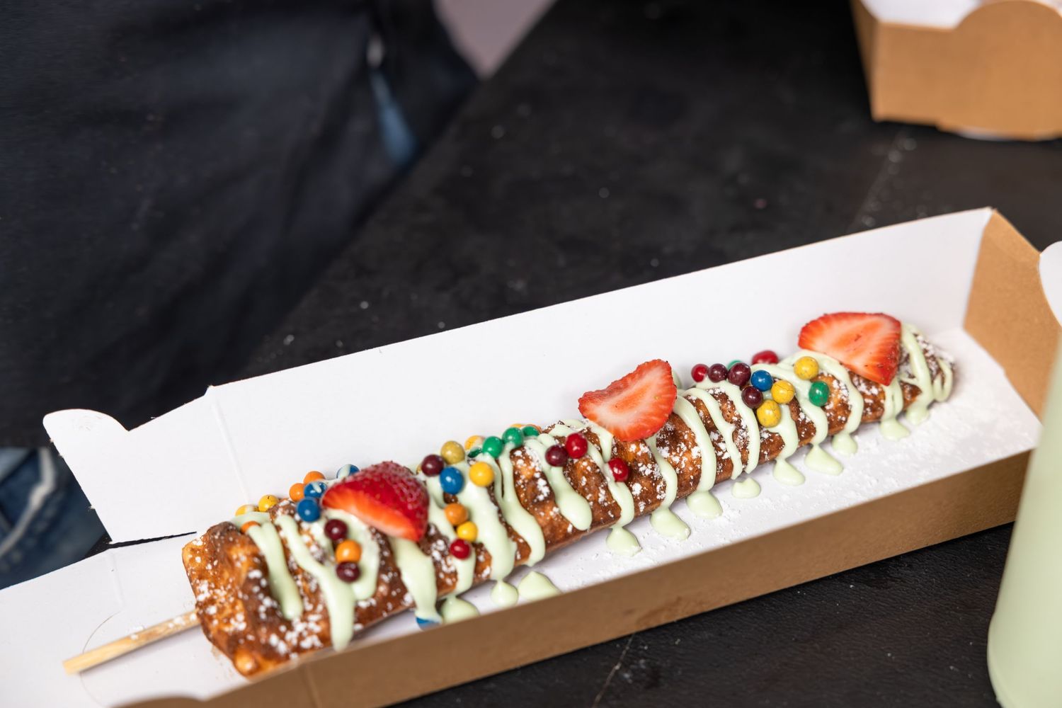 Close-up of skewered food items with colorful sauces and toppings in white serving containers.