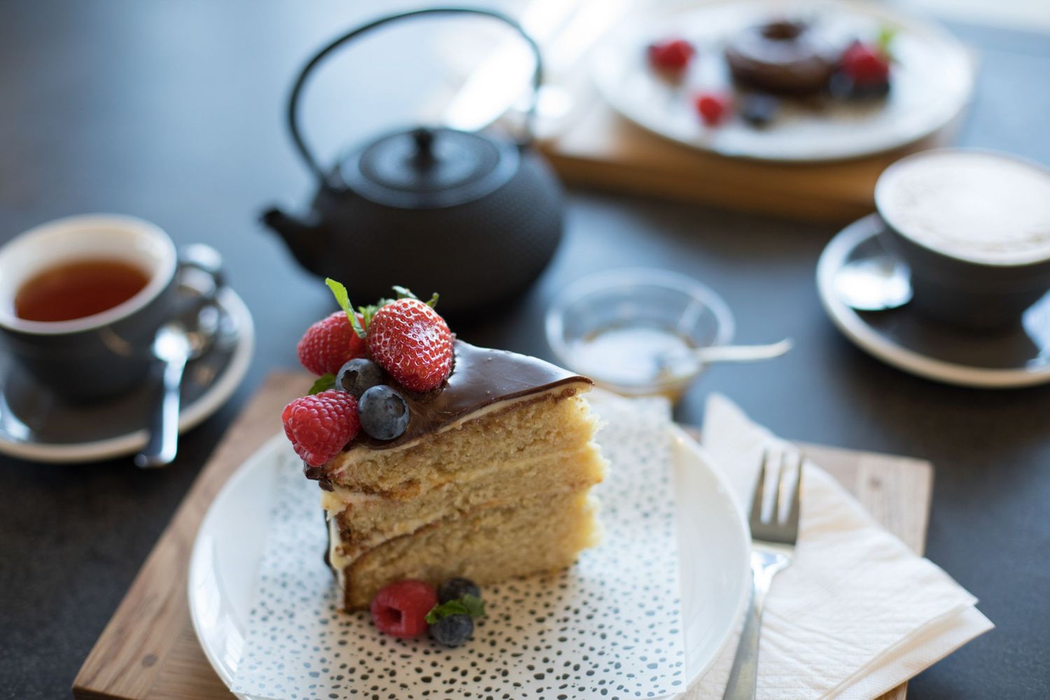Slice of cheesecake topped with fresh berries served on elegant white plates.