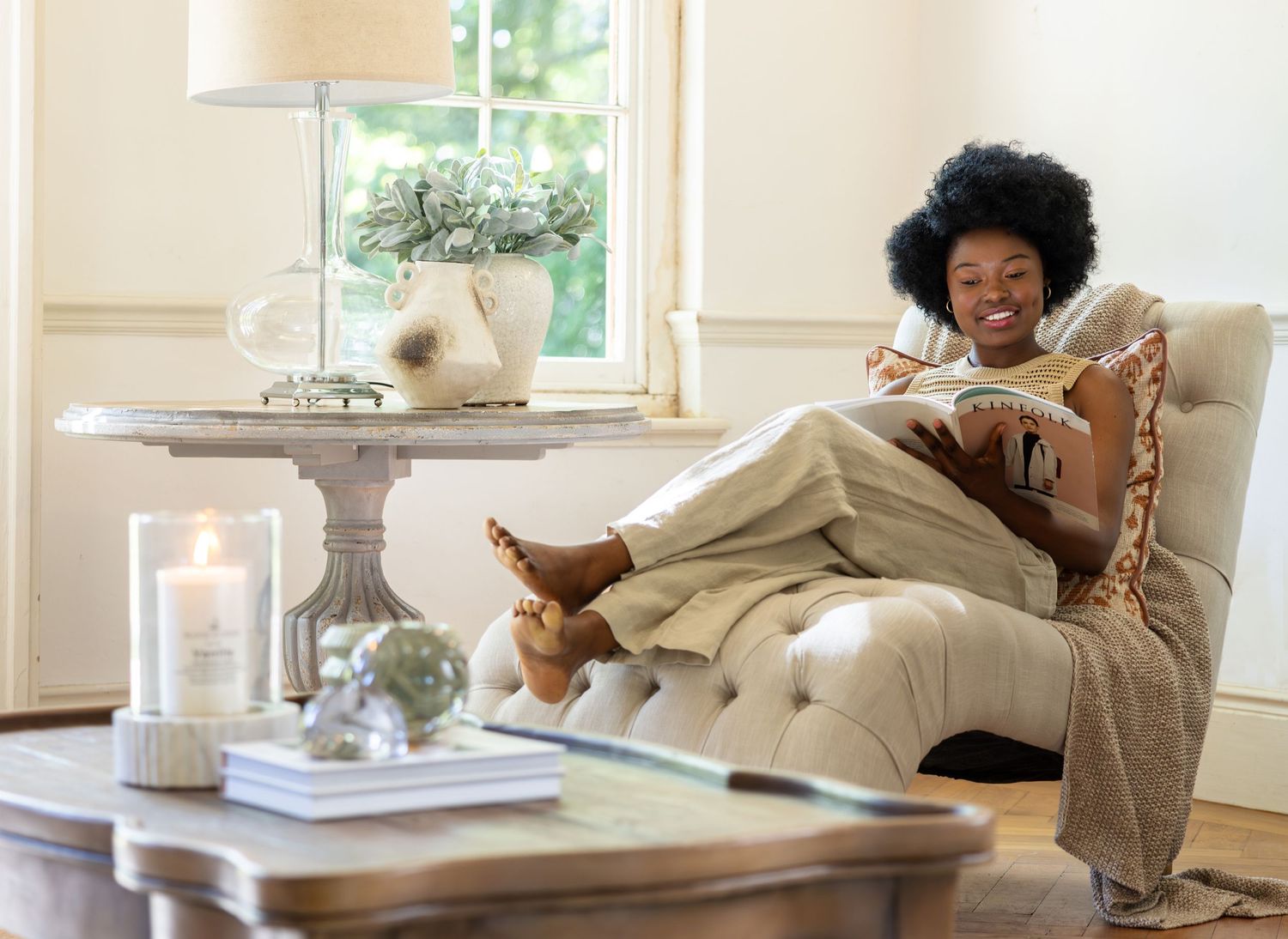 A person relaxes comfortably with a book on a beige sofa in a bright and airy living room.
