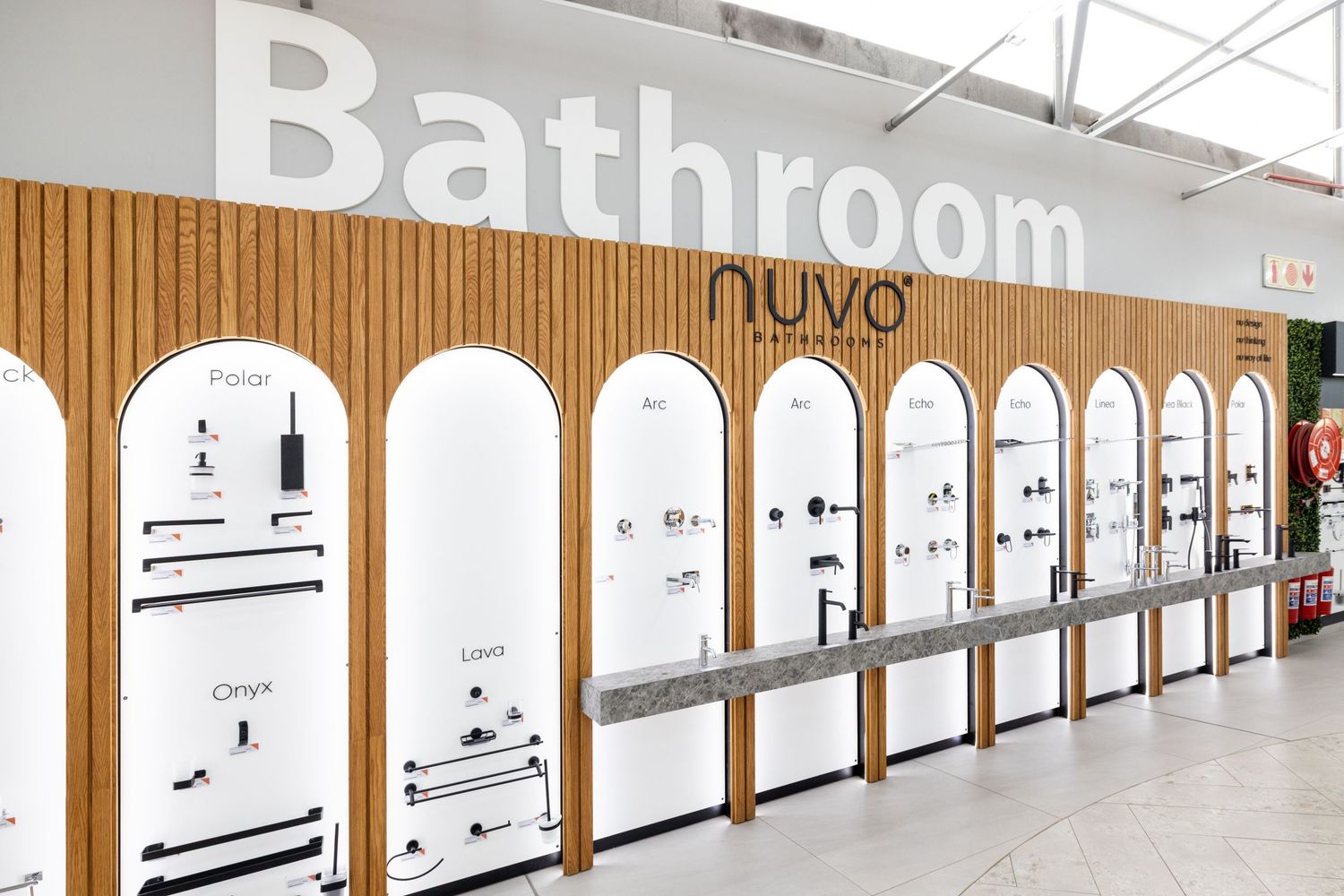 Modern bathroom showroom displaying sleek fixtures and faucets mounted on white walls with wood accent panels.