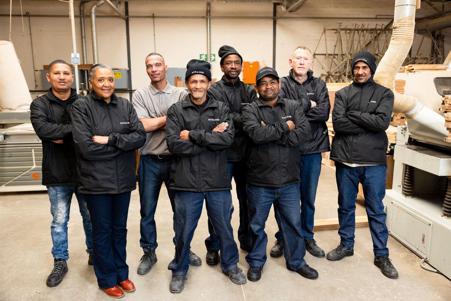 Production team members lined up against a wall in a manufacturing facility.