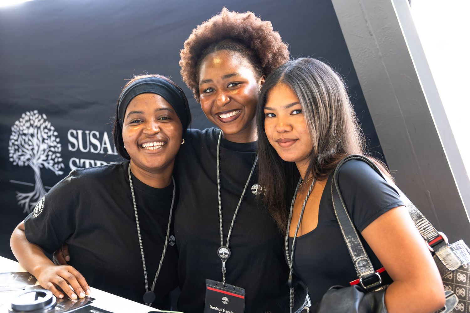 A group of people in black shirts pose together at a professional event with a SUSA logo visible.