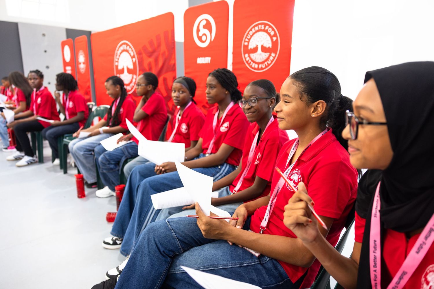 Students in red uniforms sit in rows during an educational program.
