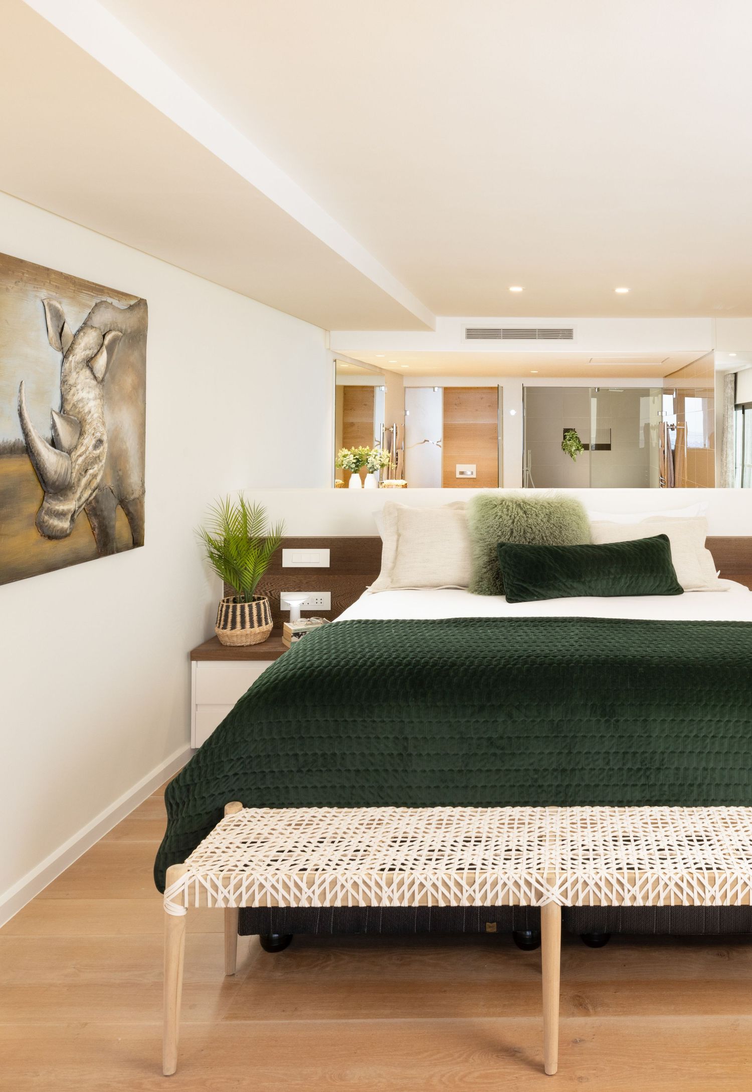 Contemporary bedroom with dark green bedding, wooden accents, and minimalist black and white animal artwork.