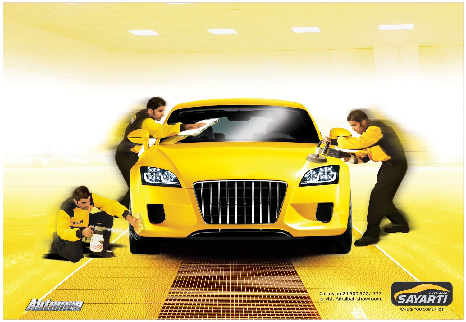 Three people in yellow uniforms clean and polish a bright yellow sports car in a service garage setting.