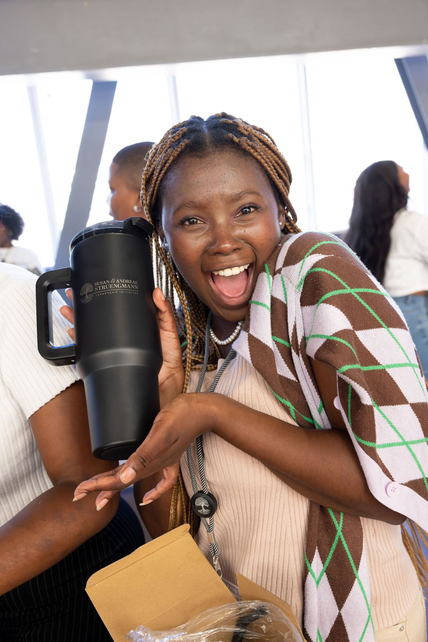 Student displays excitement while holding a large travel mug during an event.