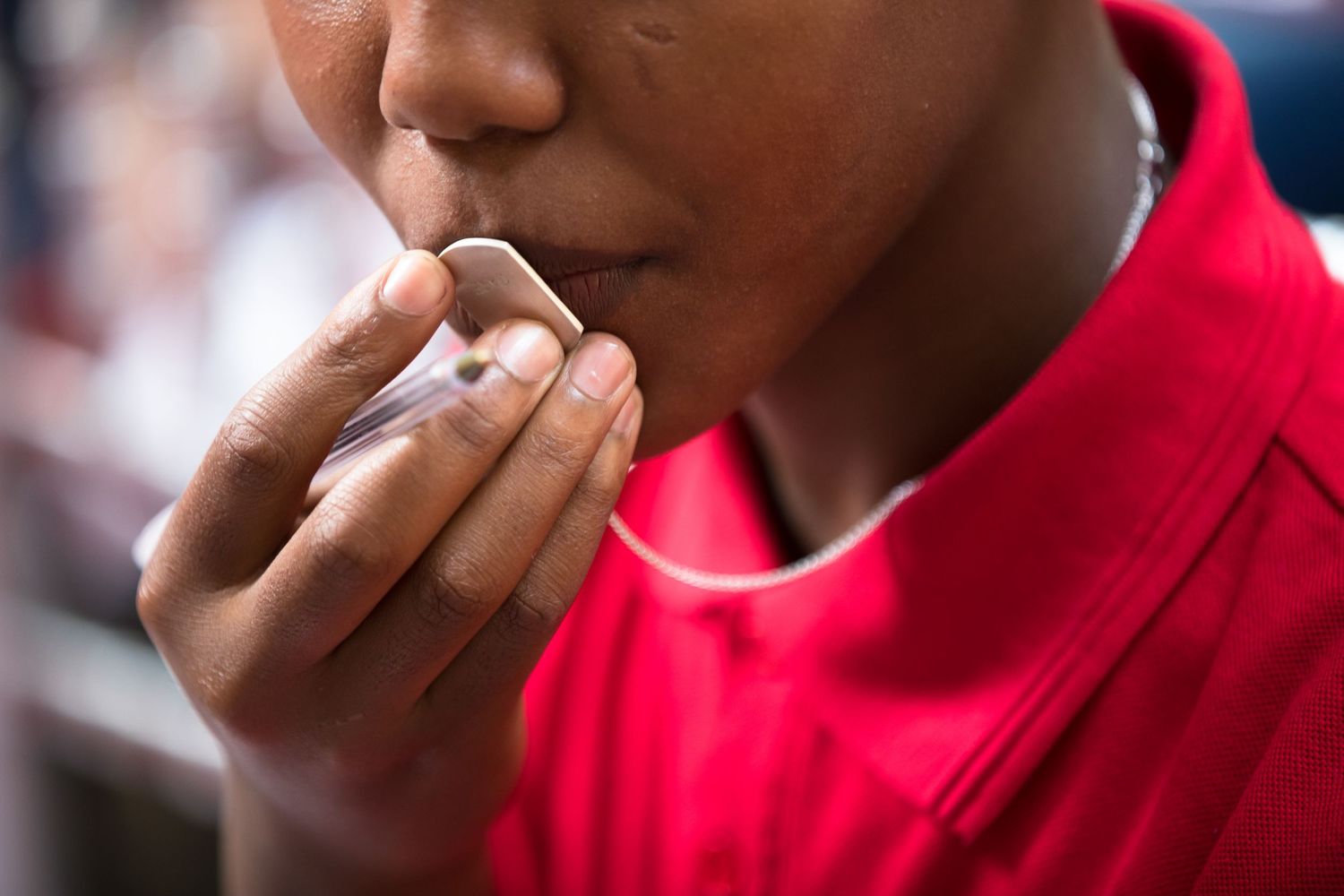 Close-up of someone in a red shirt applying lip balm.