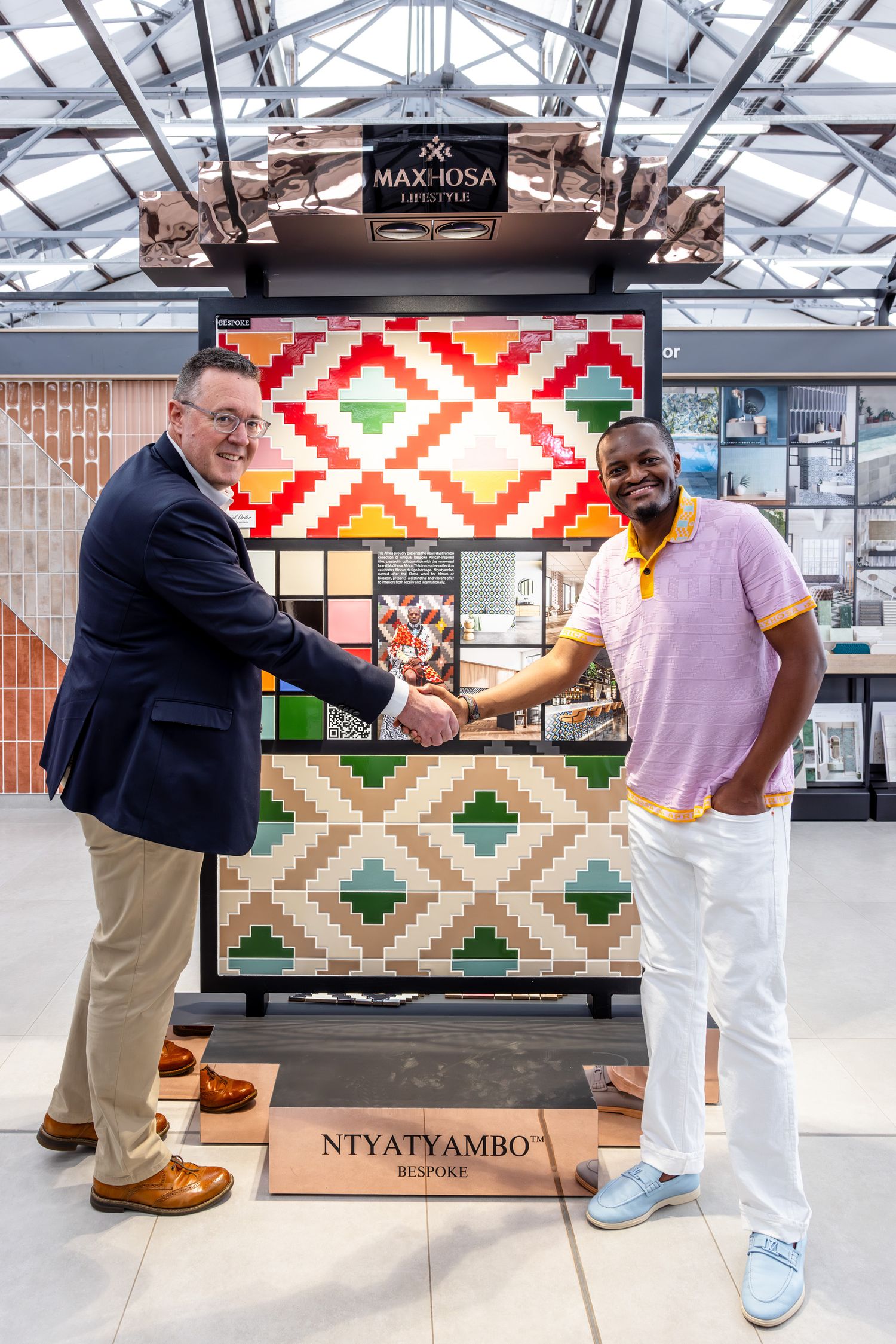 Corporate meeting in front of colorful geometric tile display with Makinsa branding.