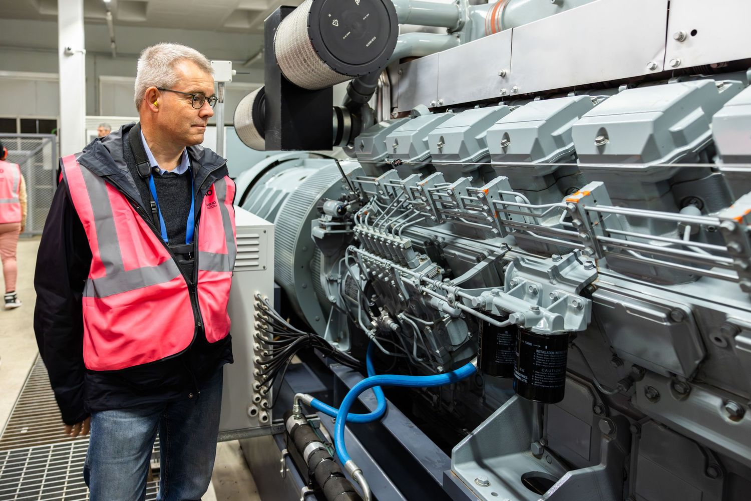 Visitor examining complex machinery and engine components in an industrial facility.