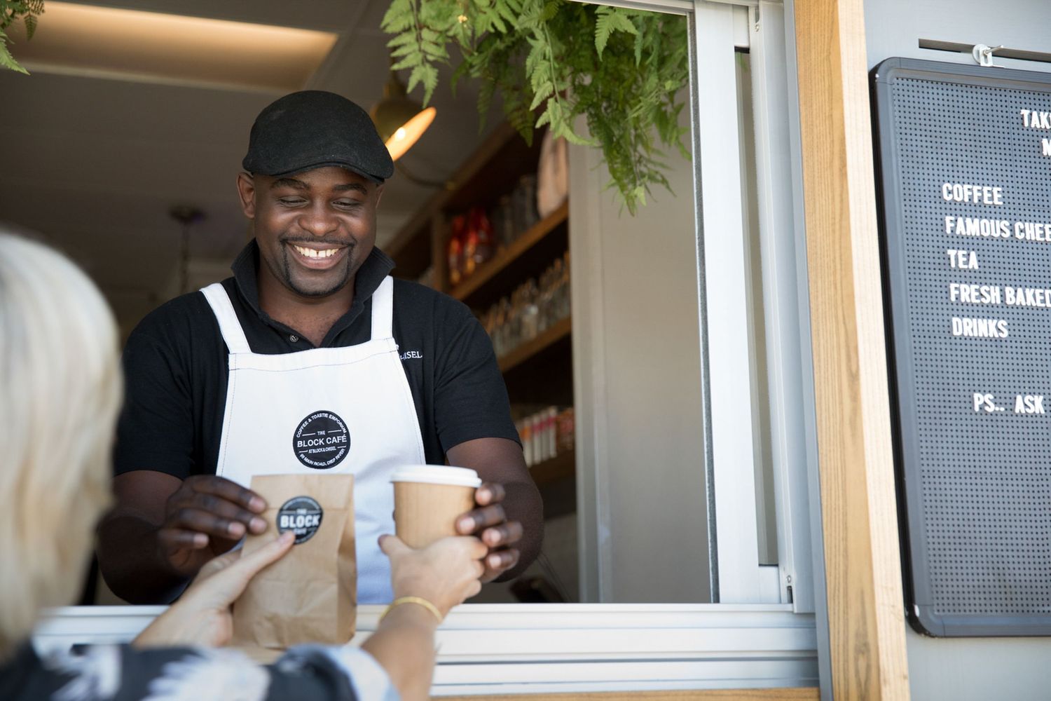 Staff members in black and white uniforms working at a cafe counter.