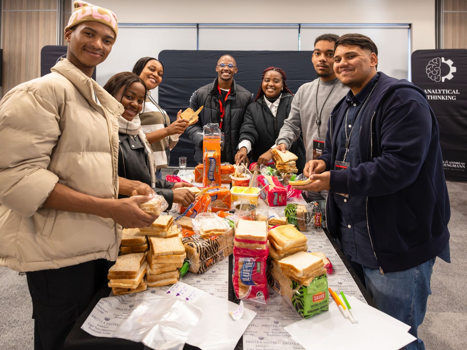 Group shares lunch together at a conference table with sandwiches and snacks.