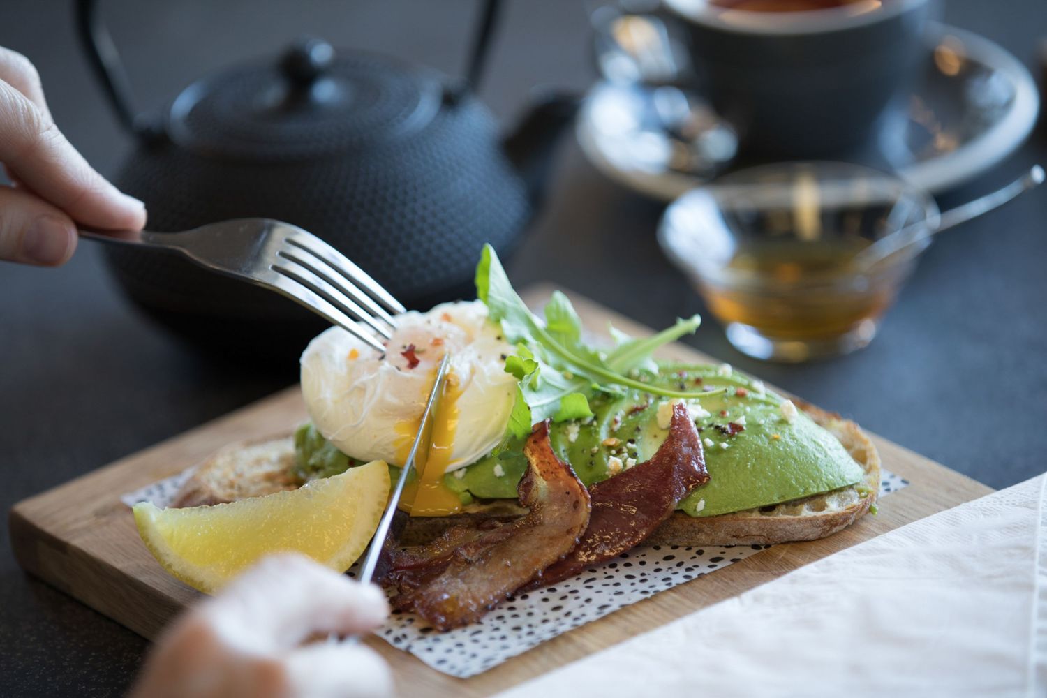 Fresh avocado toast garnished with microgreens served on wooden cutting board.