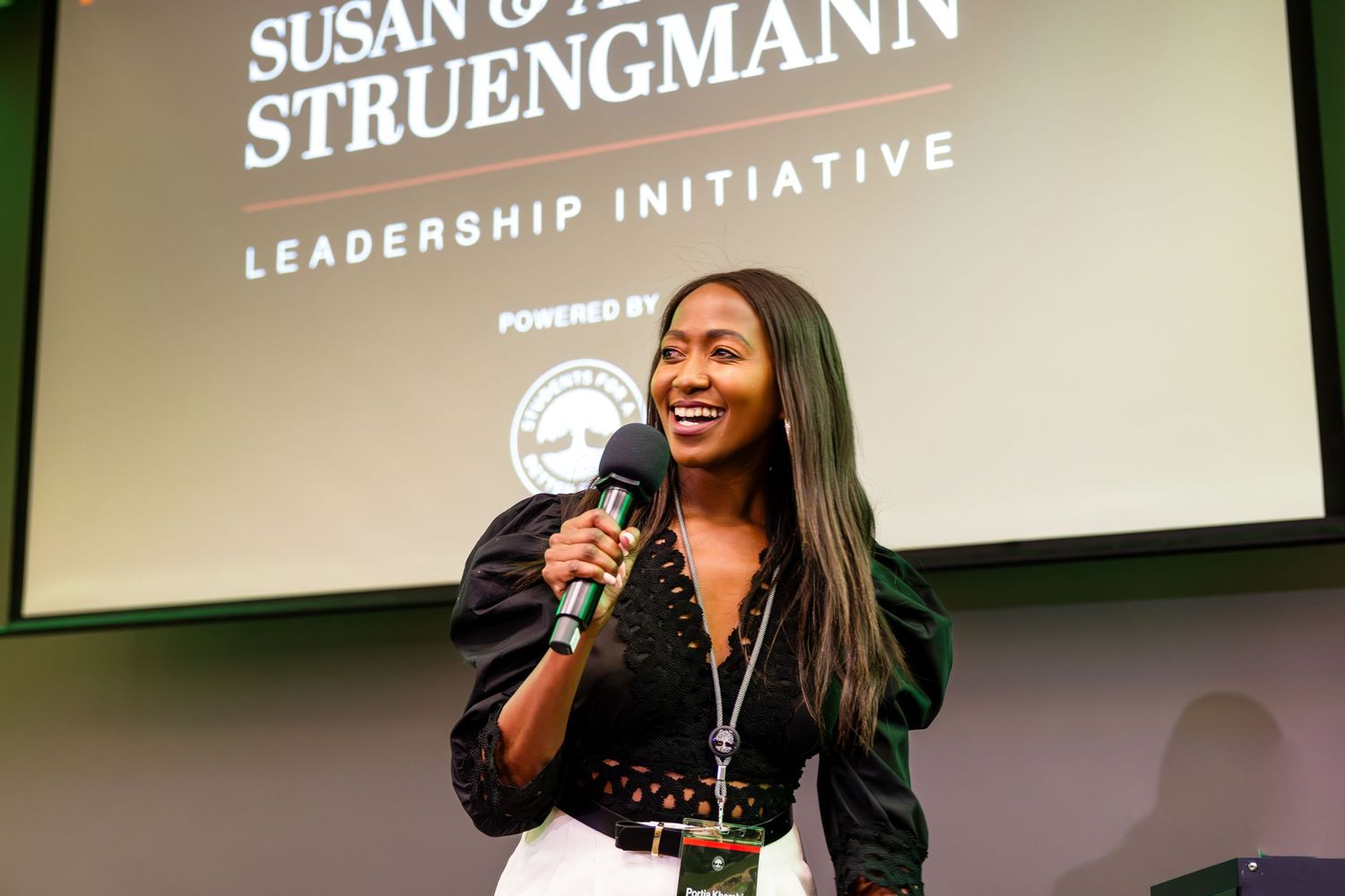 Speaker presenting at leadership initiative event with projected text visible.