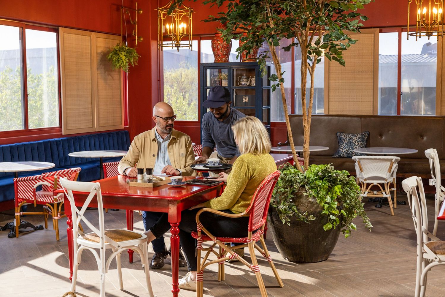 An elegant restaurant interior with chandeliers, plants and tables set for dining.