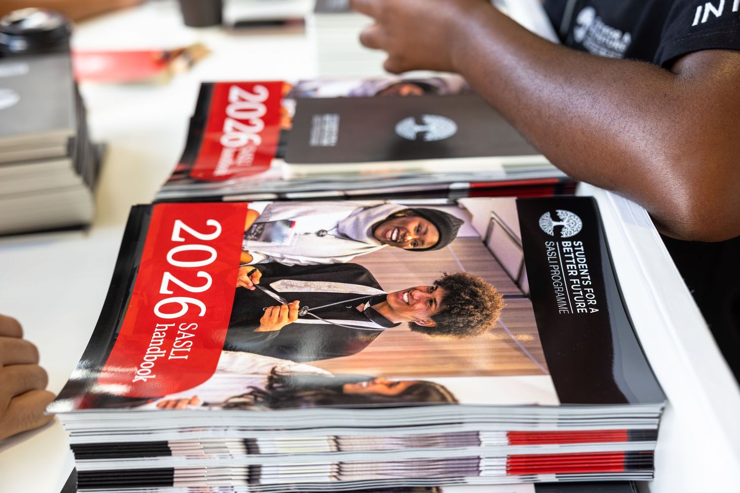 Stack of glossy magazines or publications being displayed on a surface with visible printed covers.