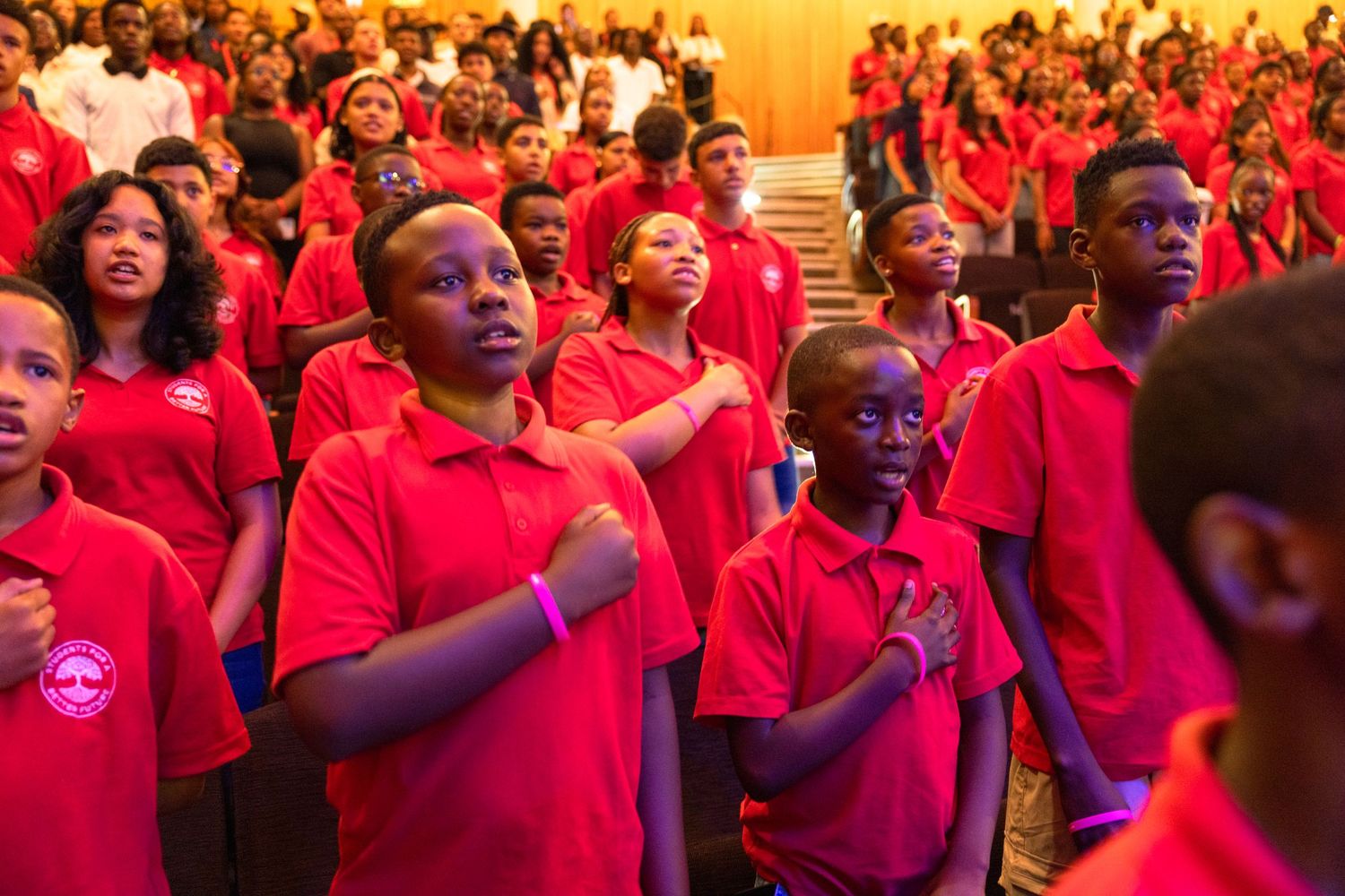 Large group of students wearing red shirts gathered at an academic ceremony.