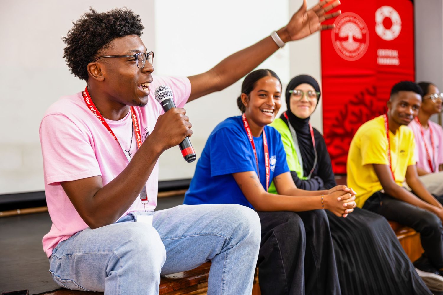 Speaker engaging with audience during a presentation with diverse participants in background.