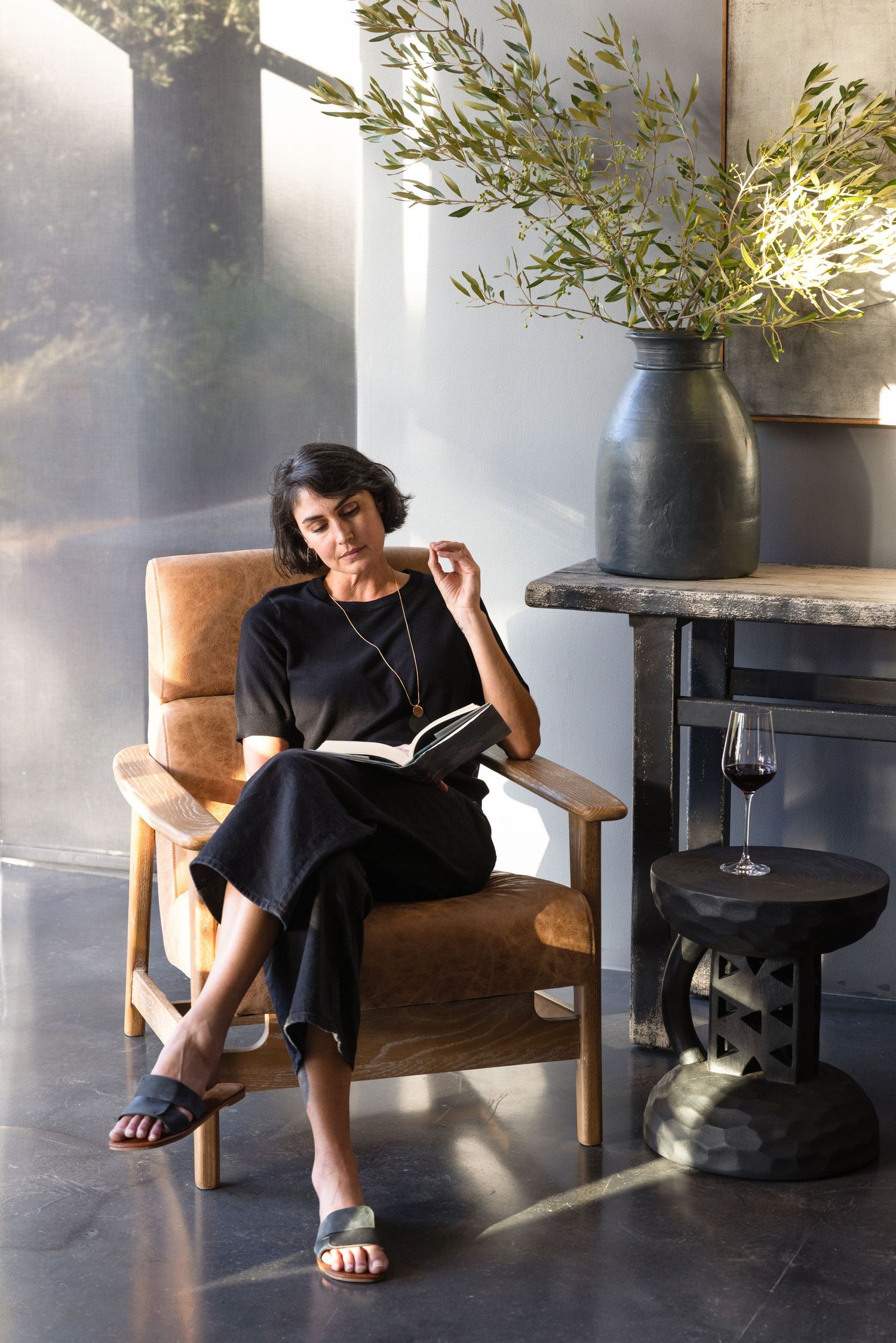 A sequence of photos showing a person dressed in black lounging casually in a brown leather chair next to potted plants.