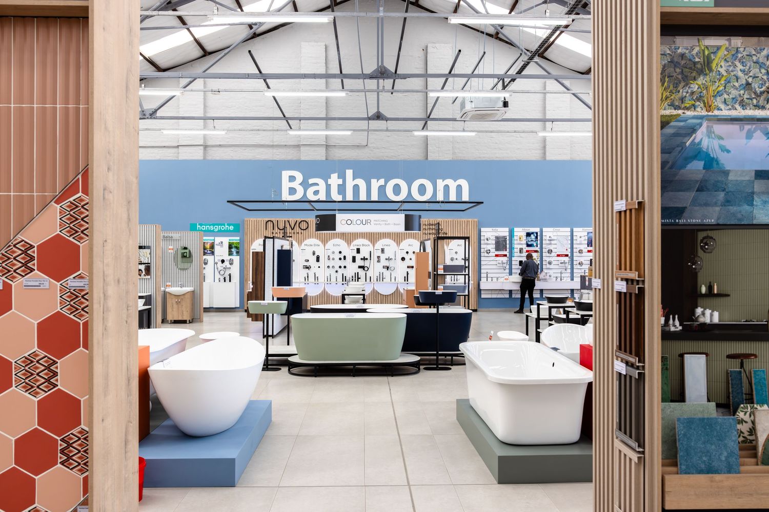 Modern bathroom showroom featuring white fixtures and red hexagonal wall accents.