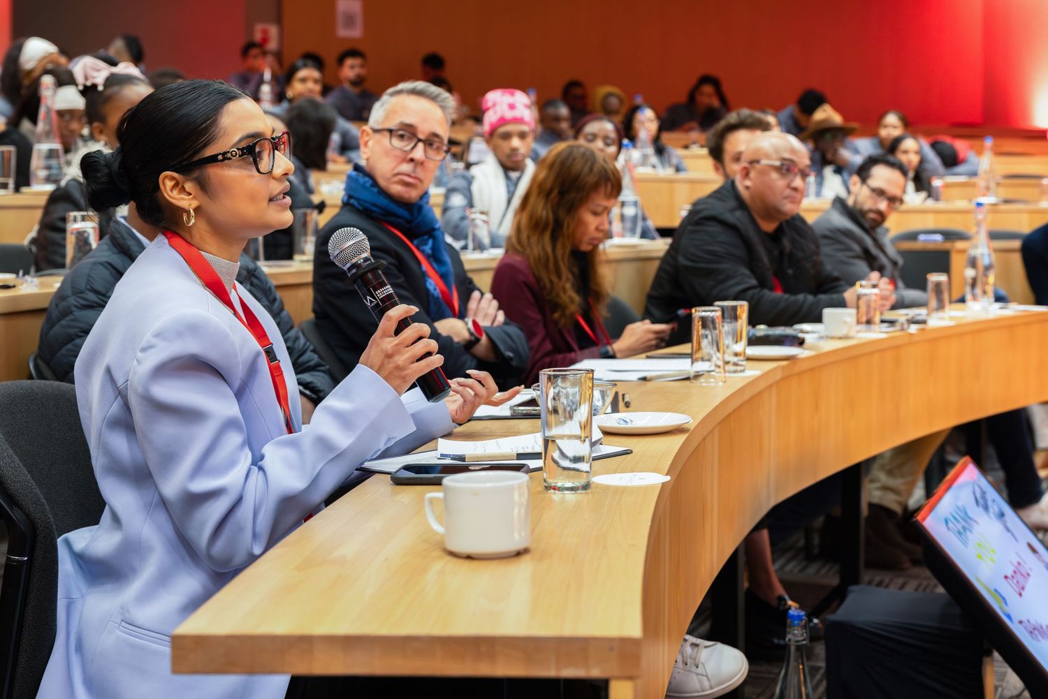 Business conference attendees seated in curved rows during a professional presentation.