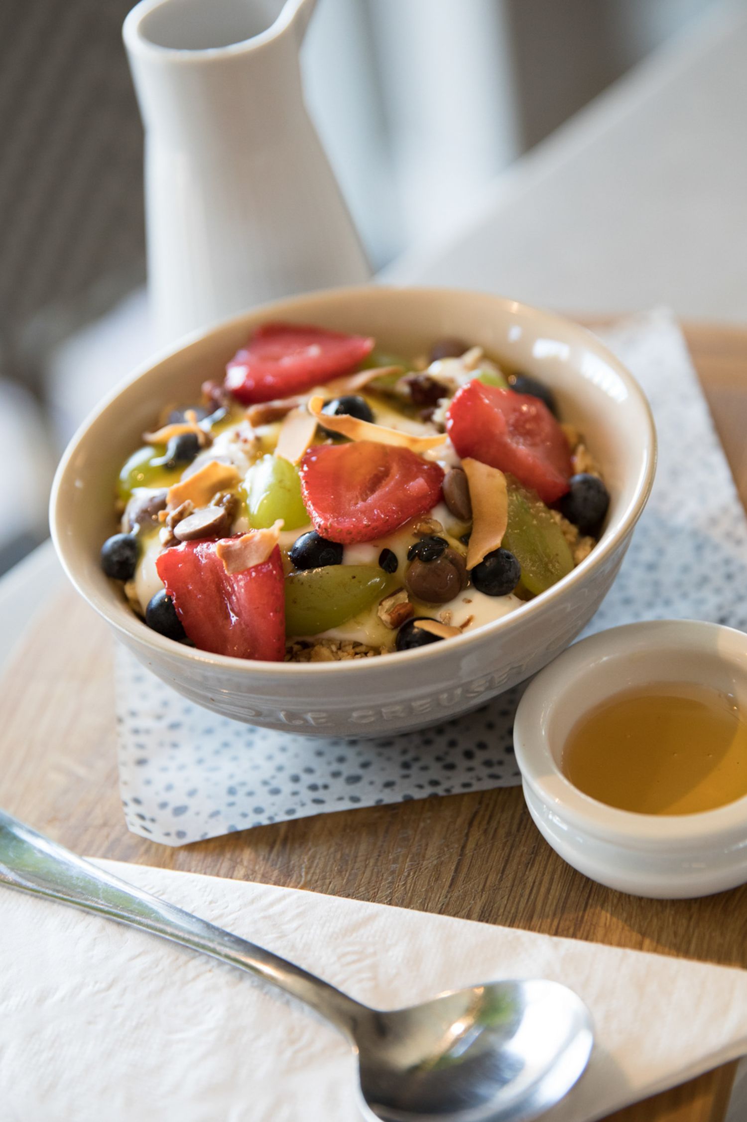 Fresh fruit salad served in a ceramic bowl with honey on the side.