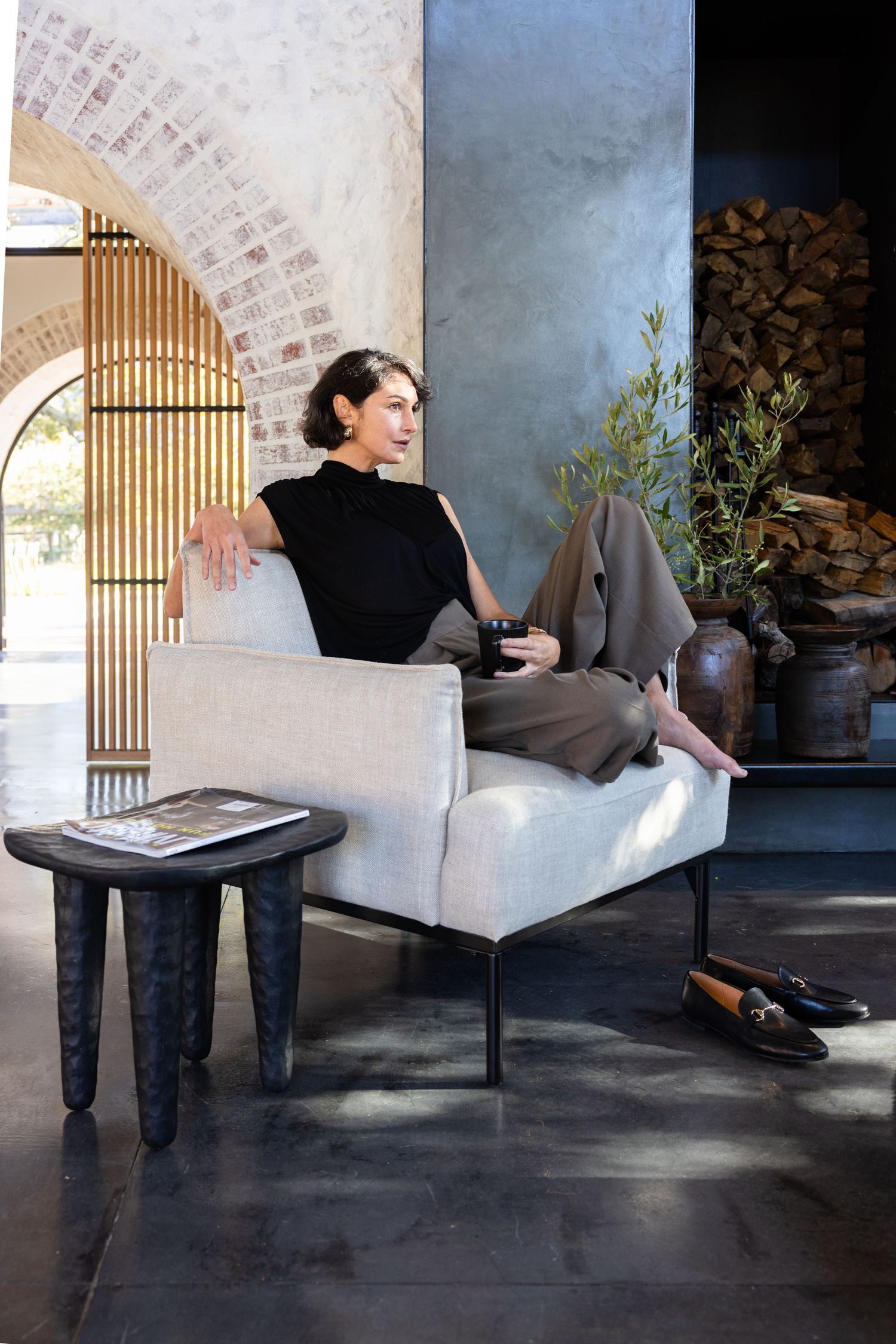 A person relaxes on a modern white sofa in an elegant space with arched doorway and dark tile floors.