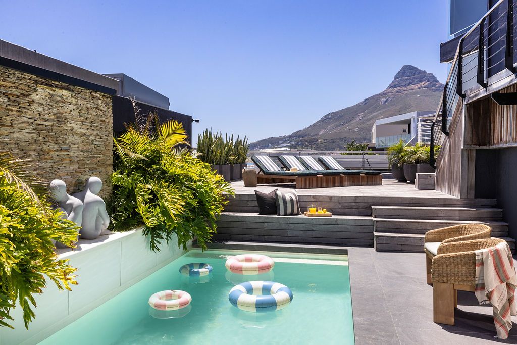Luxurious infinity pool overlooking scenic mountain landscape with modern lounge chairs and umbrellas on sunny day.