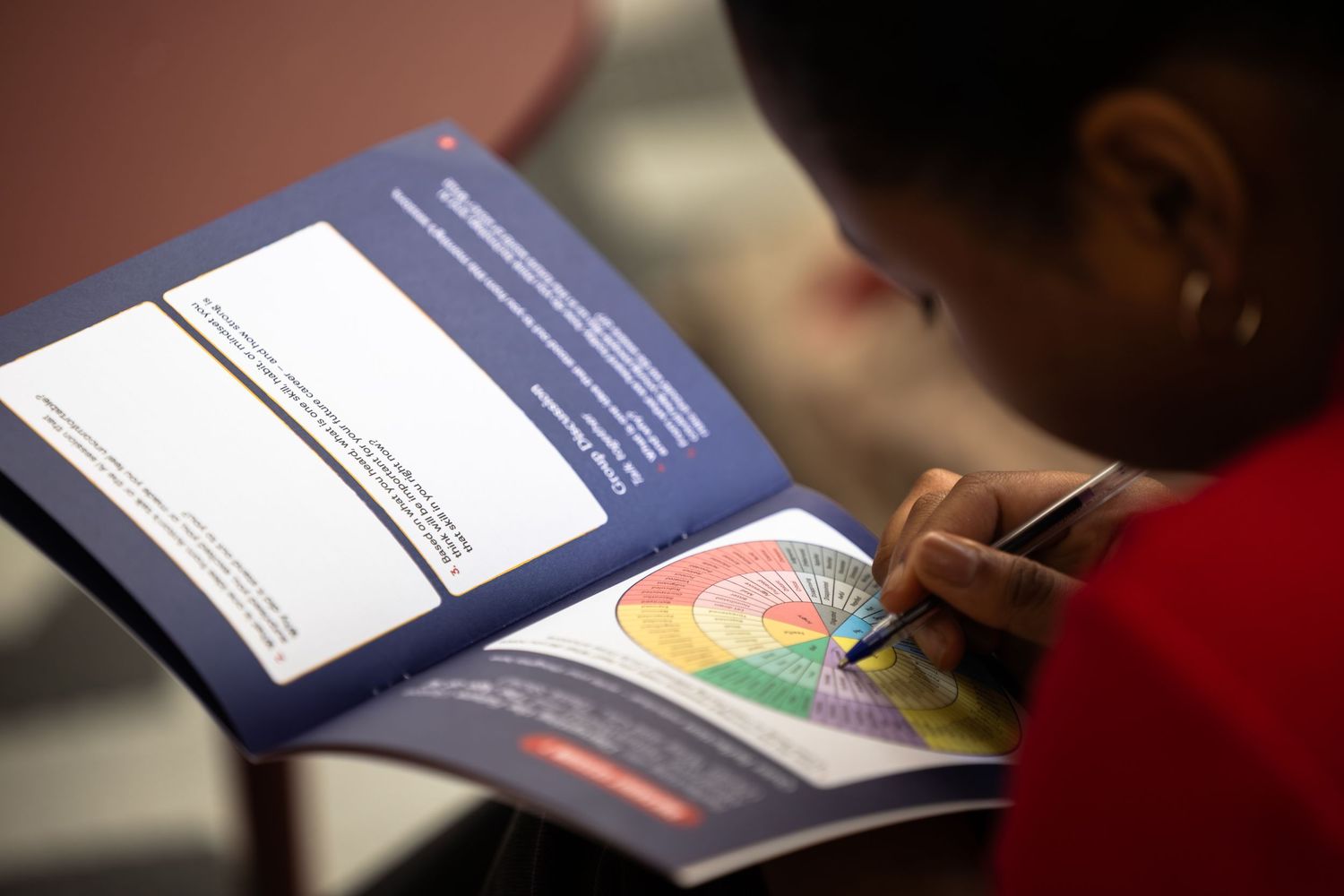 Students work on assignments at their desks with papers and textbooks spread out in a classroom setting.