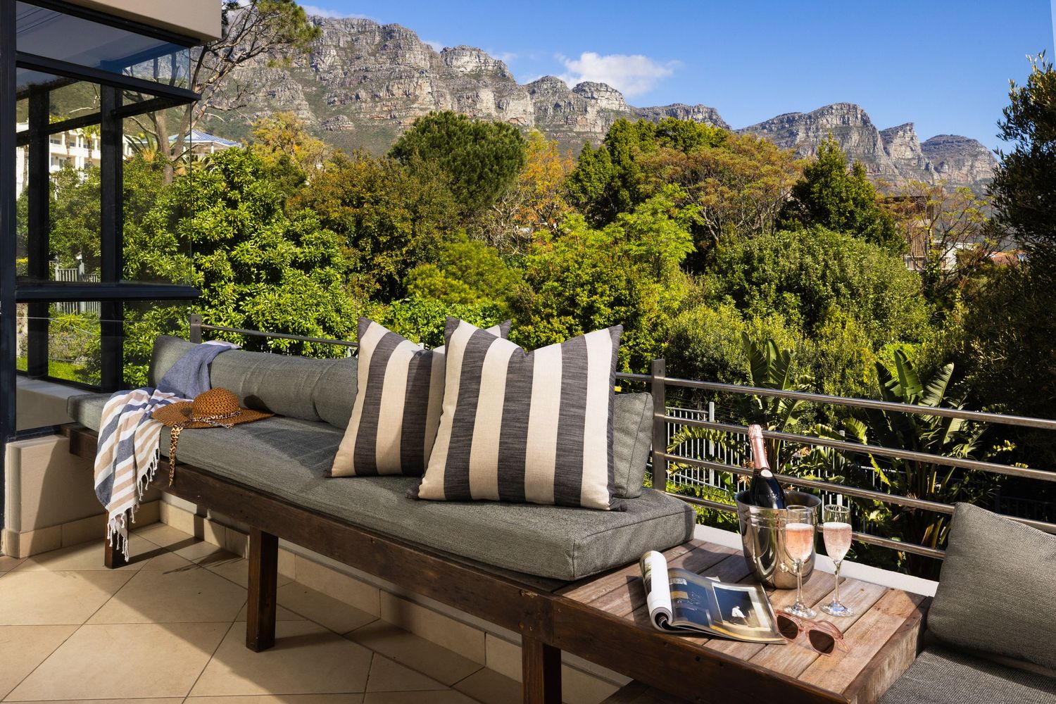 Cozy outdoor patio seating with striped pillows overlooking dramatic mountain views and lush garden landscape.