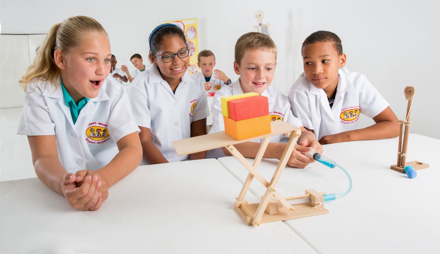 Students in lab coats observe a wooden catapult experiment with enthusiasm.