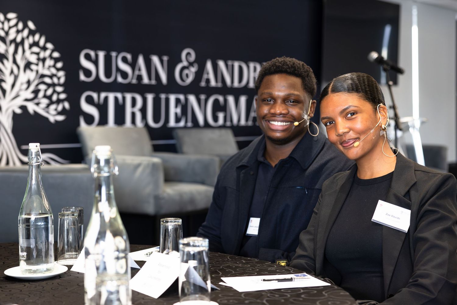 Professional conference setting with company branding and attendees in discussion.