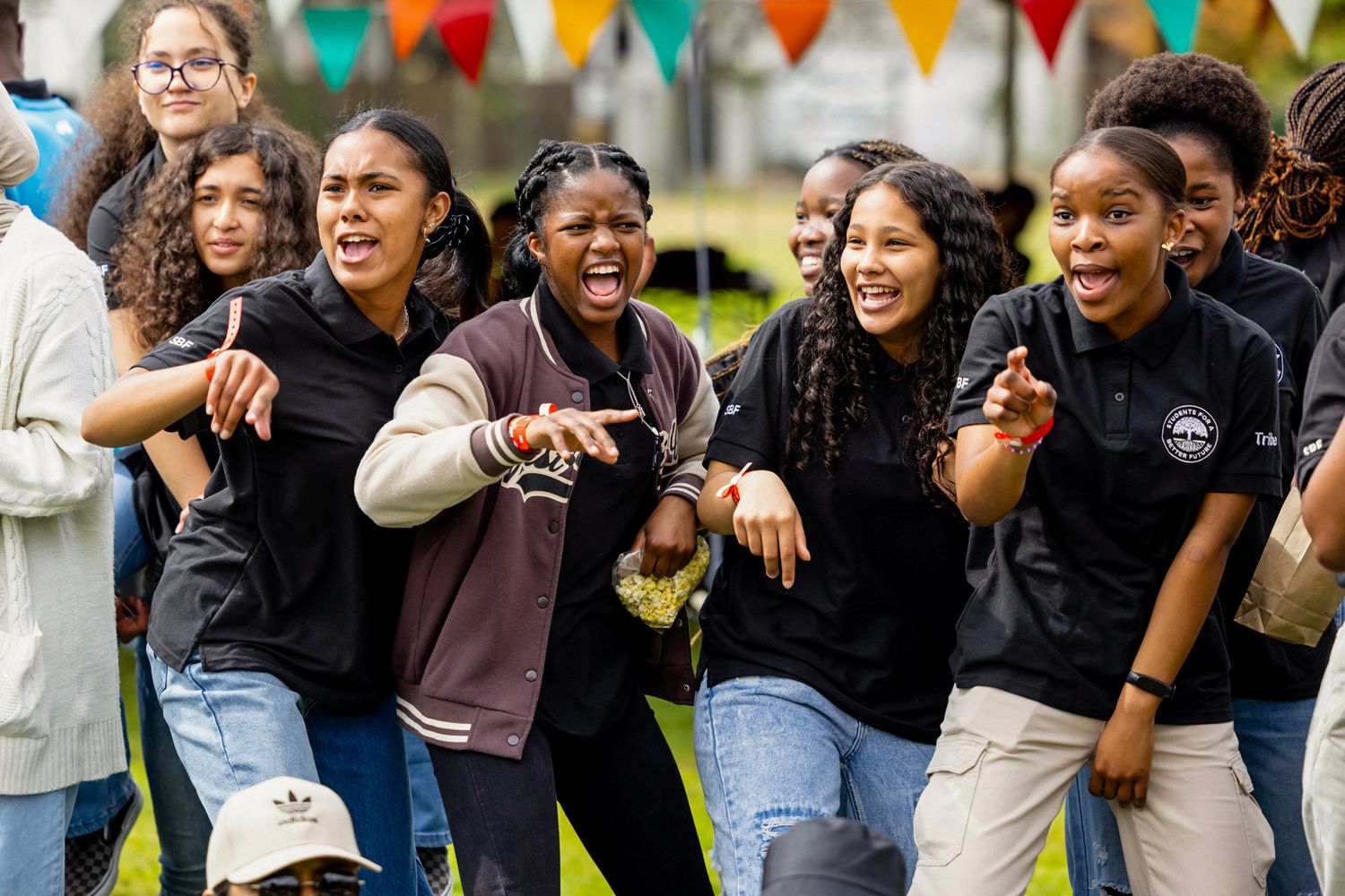 Group of students laugh together at outdoor event with festive bunting decorations.