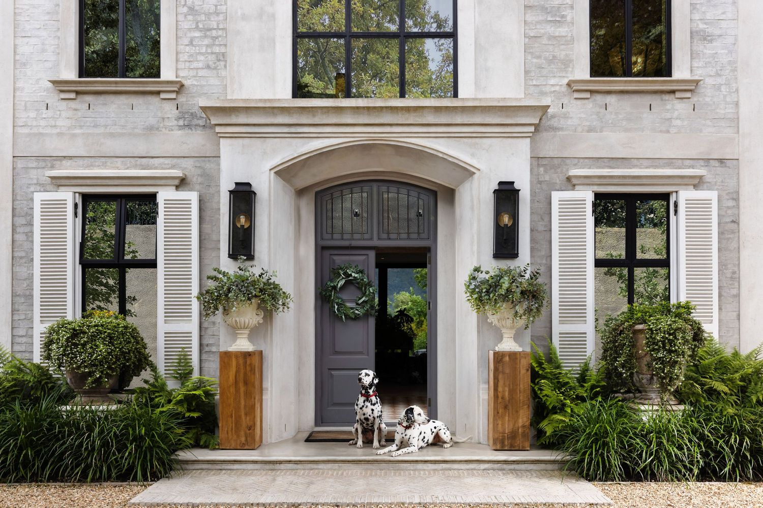 Elegant white brick house entrance with two spotted dogs sitting at the front door.