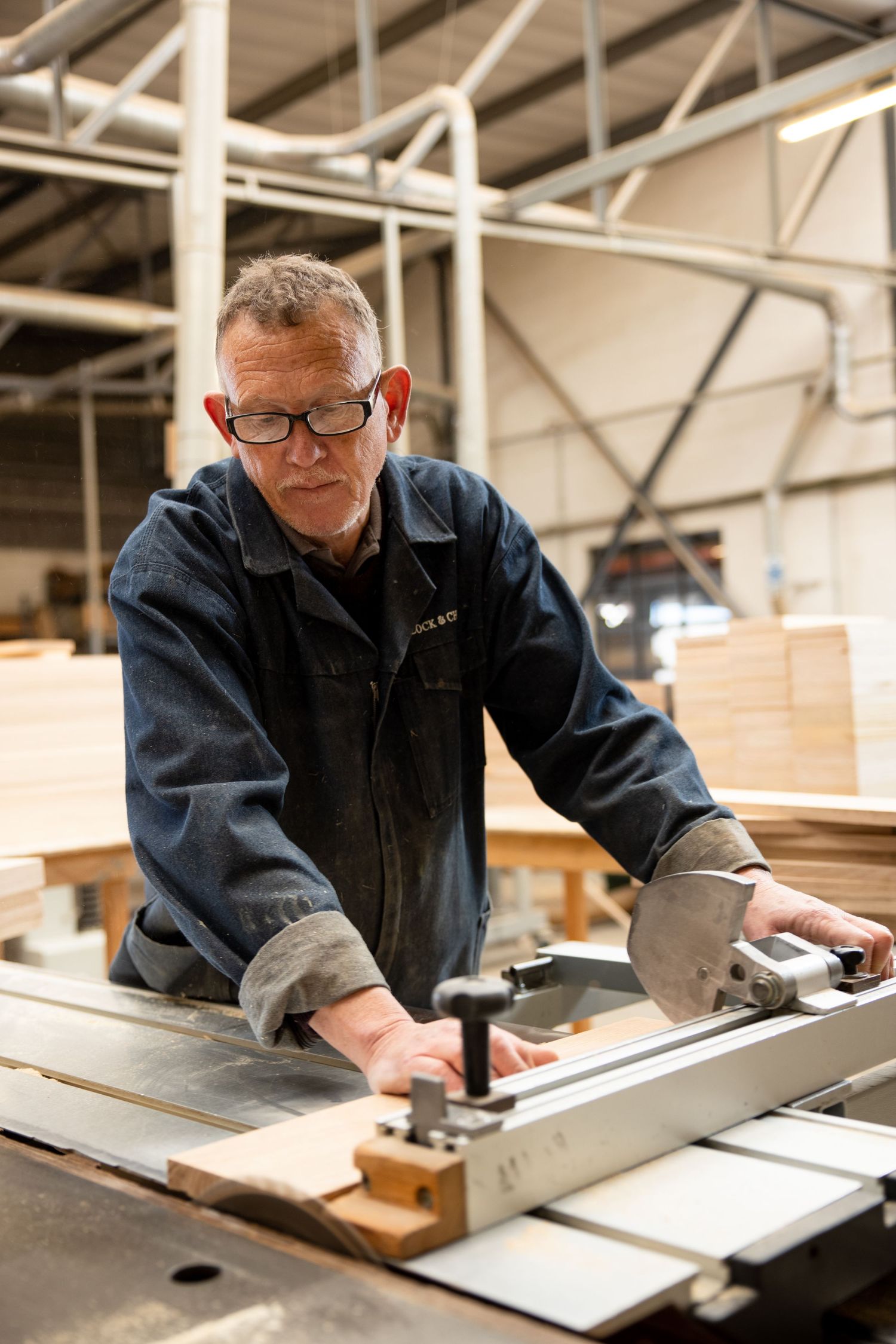Worker in blue uniform operating machinery in a woodworking factory.