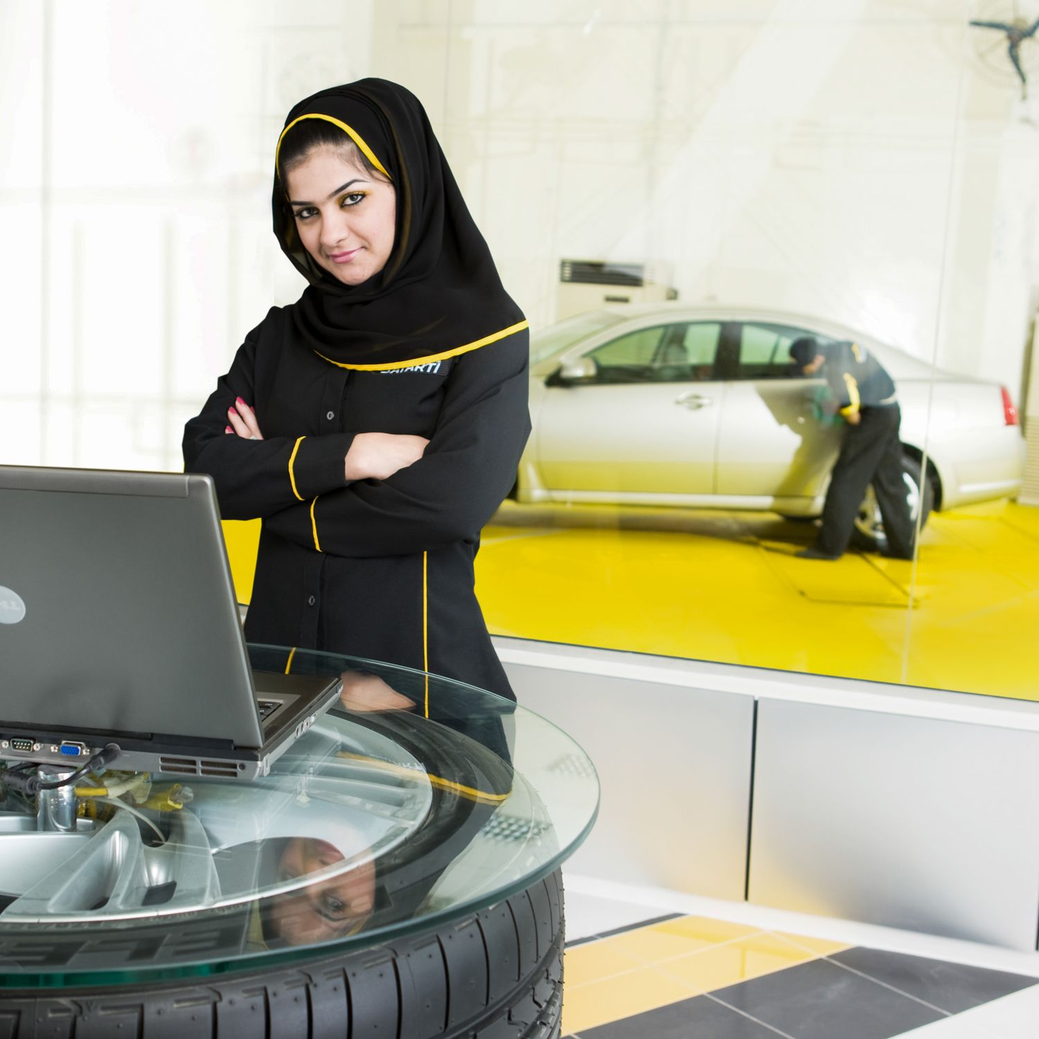 Professional automotive service advisor working at desk with computer and tire display.