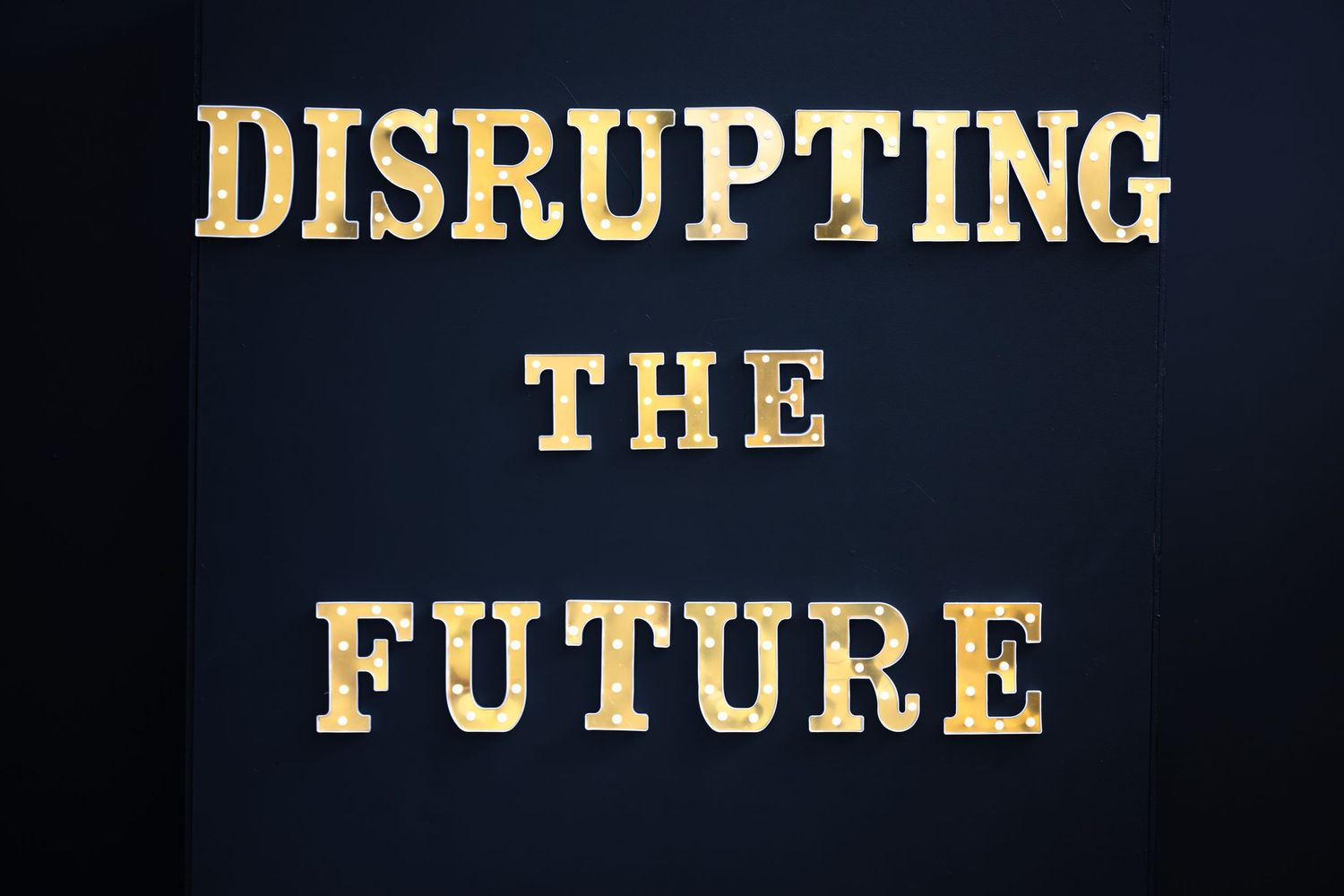 Gold metallic text reading 'DISRUPTING THE FUTURE' appears on a dark background with dramatic lighting.