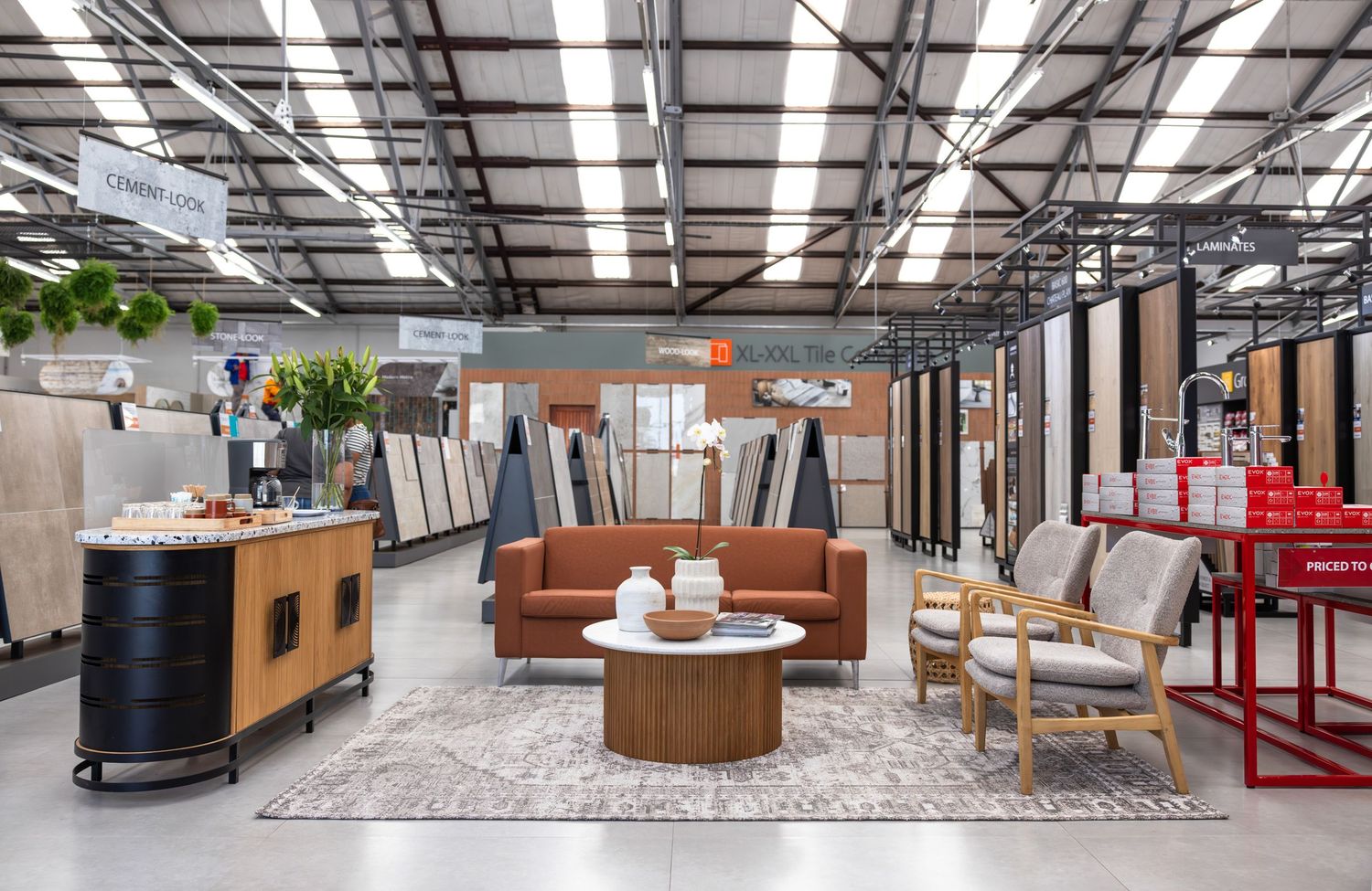 Spacious retail showroom interior with modern furniture displays and high industrial ceiling.