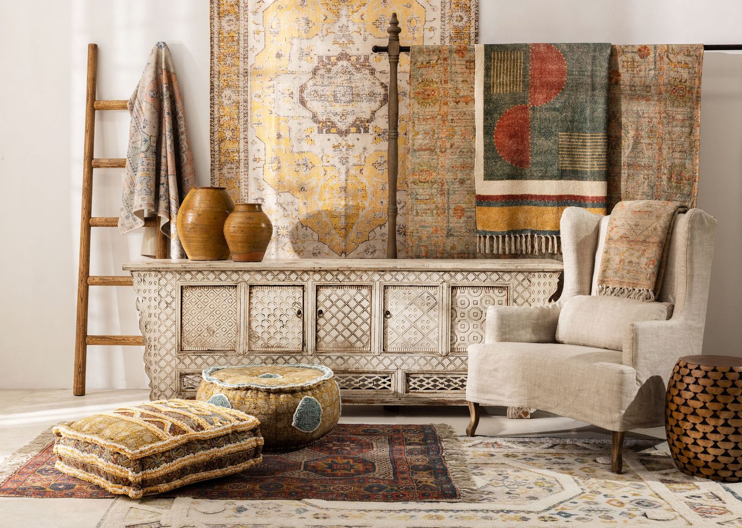 A cozy boho living space with vintage rugs, carved wooden furniture, patterned textiles, and earthy decor elements.