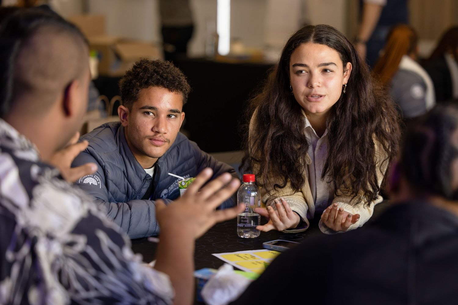 Small group engaged in conversation around table during workshop session.