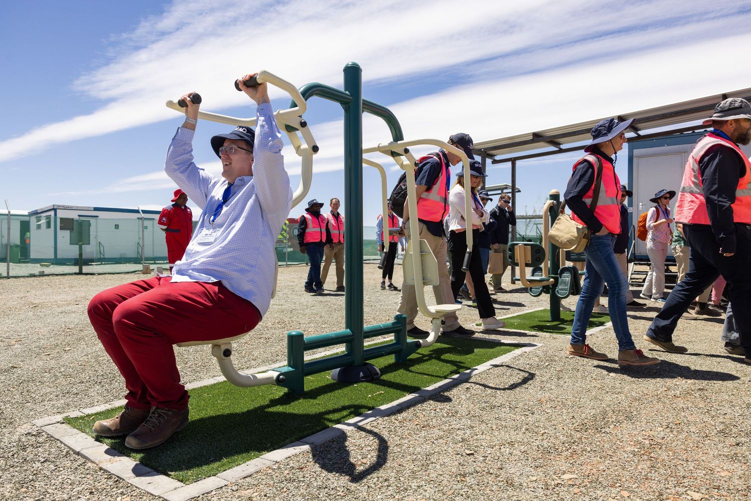 Visitors explore exercise equipment and exhibits at an outdoor science facility under blue skies.