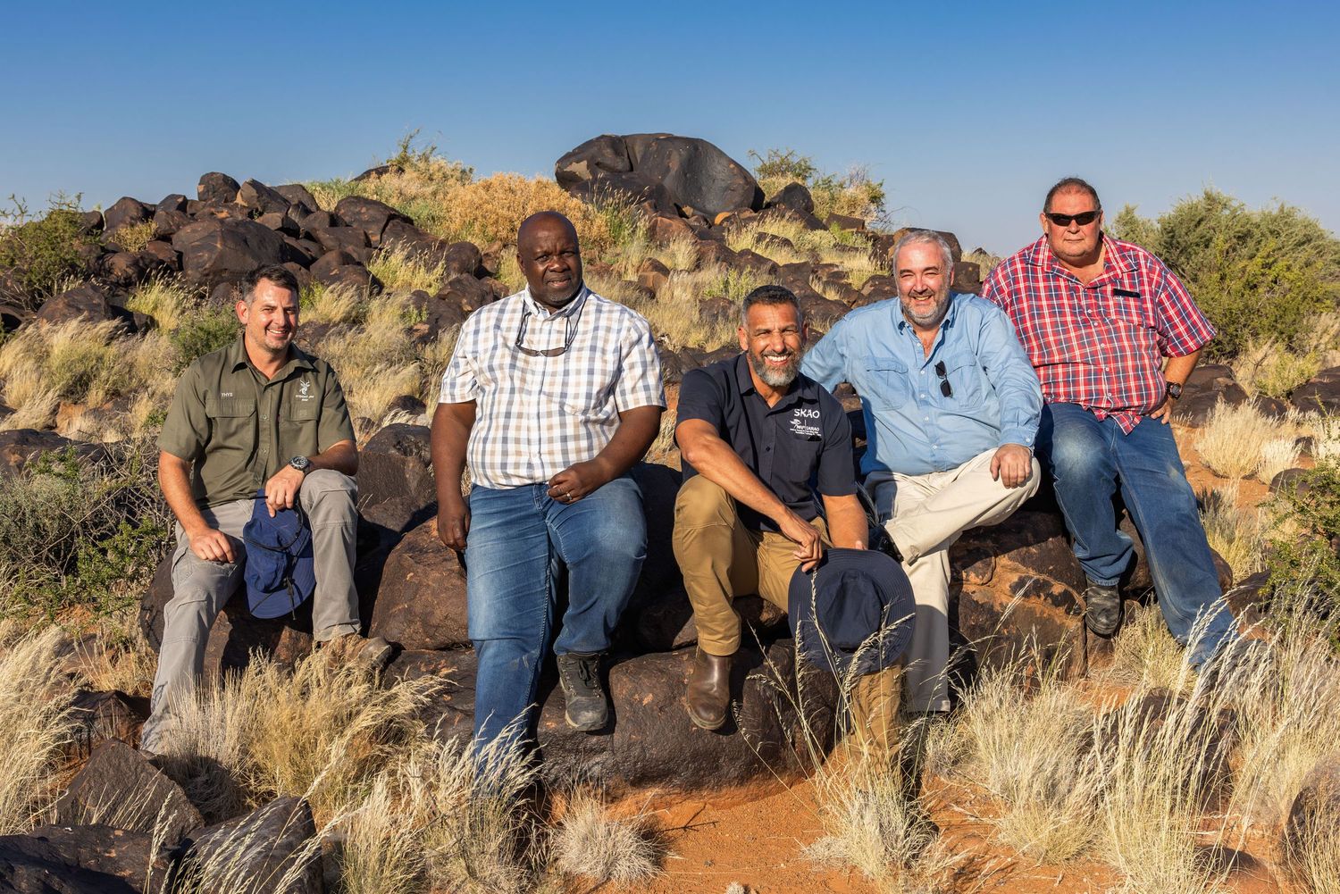 Group posing together on rocky outcrop in desert landscape.