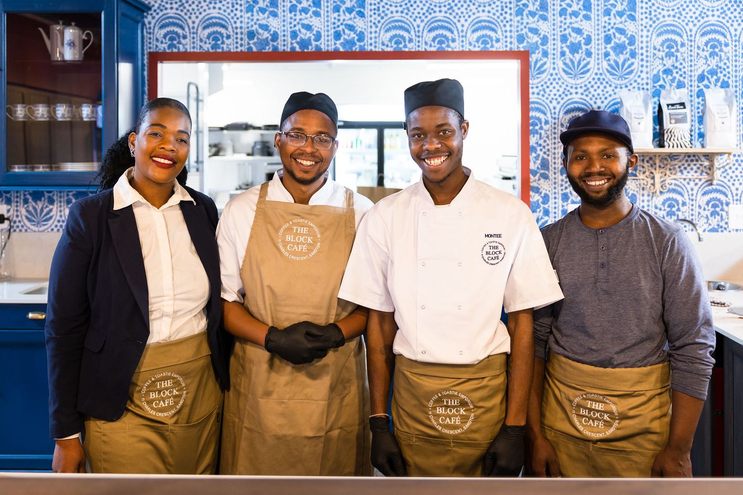Staff members wearing brown aprons pose together at The Block Cafe.