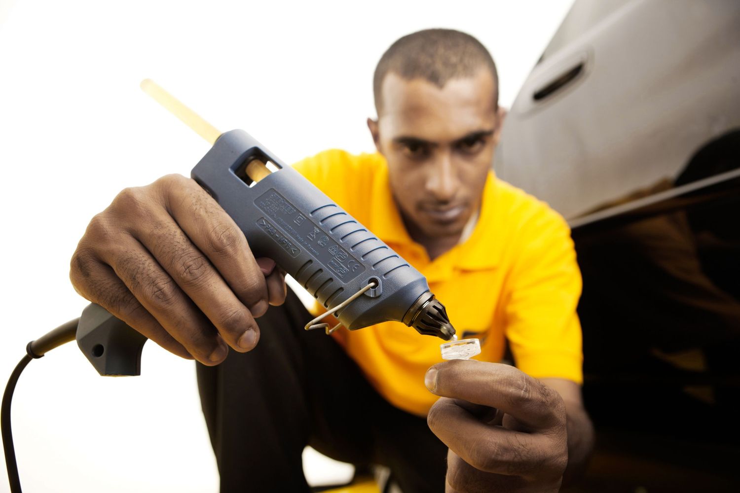 Auto repair technician using glue gun for vehicle maintenance work.