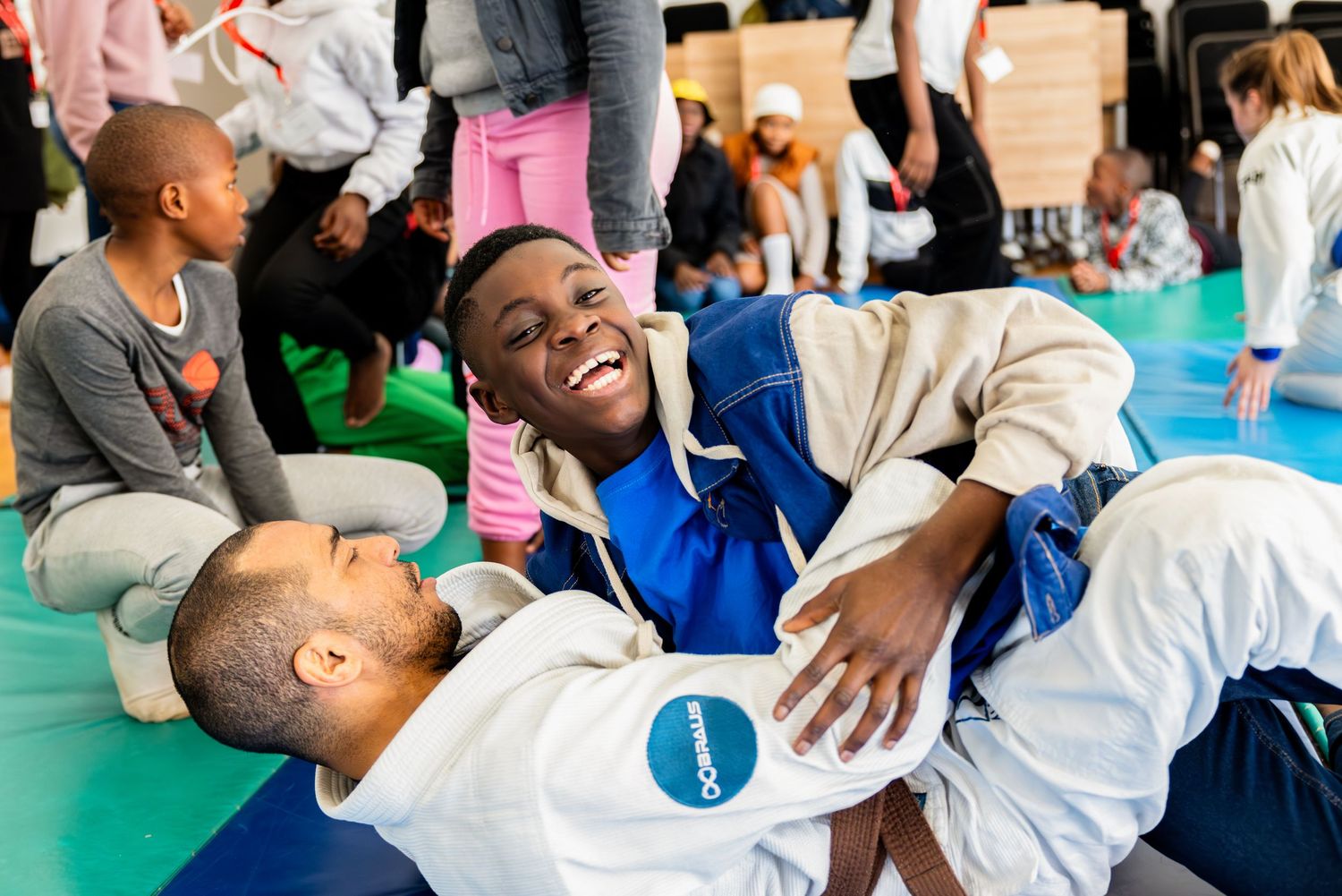 Students practice jiu-jitsu moves on training mats during a martial arts class.