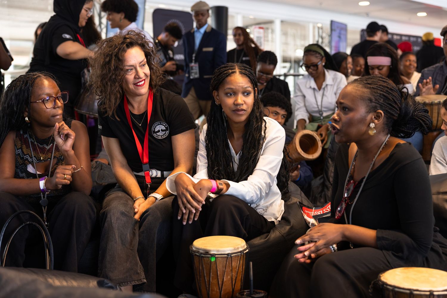 Diverse group of participants engage in drumming activities at a workshop event.